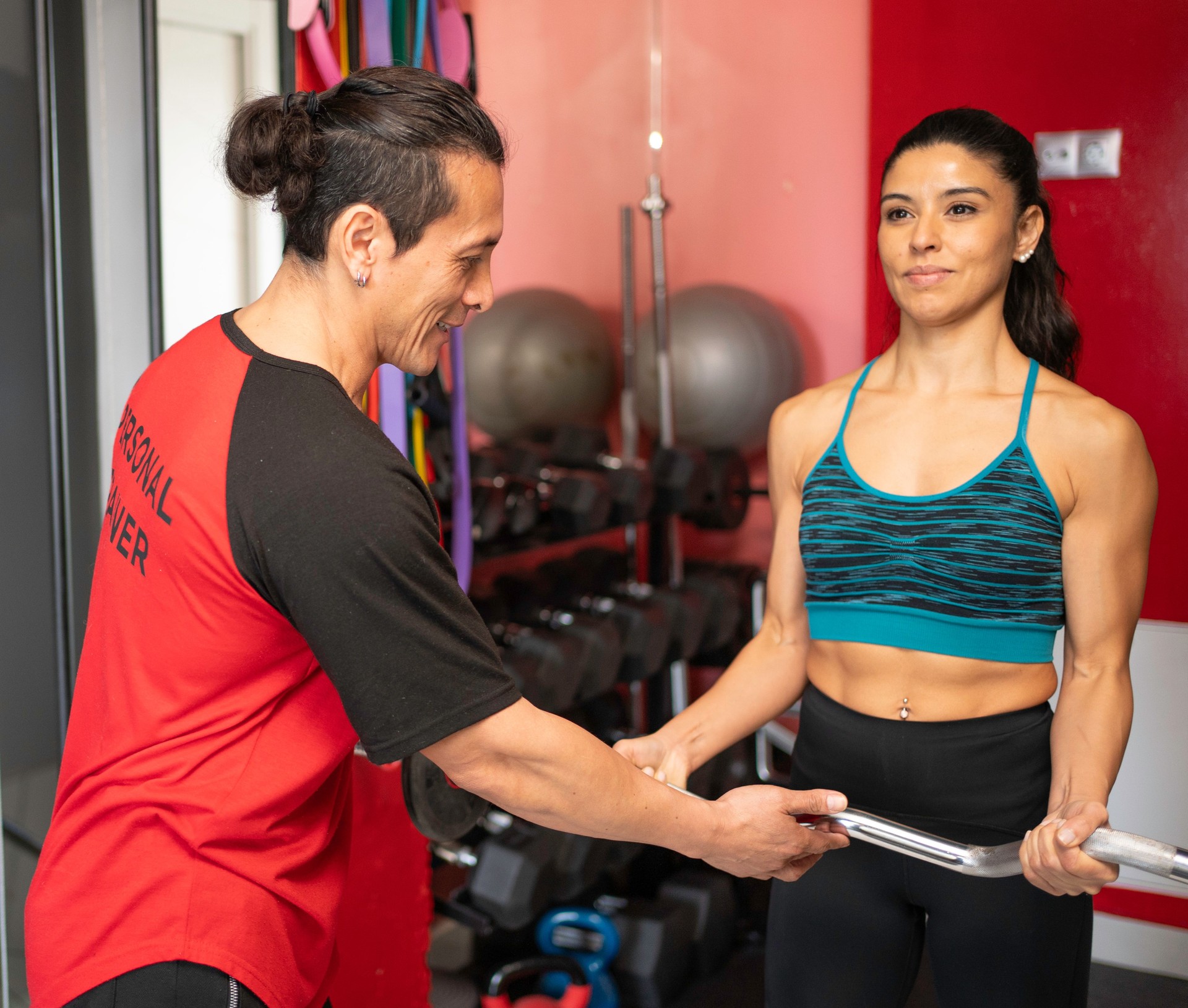 Personal trainer assisting female client lifting weights in gym