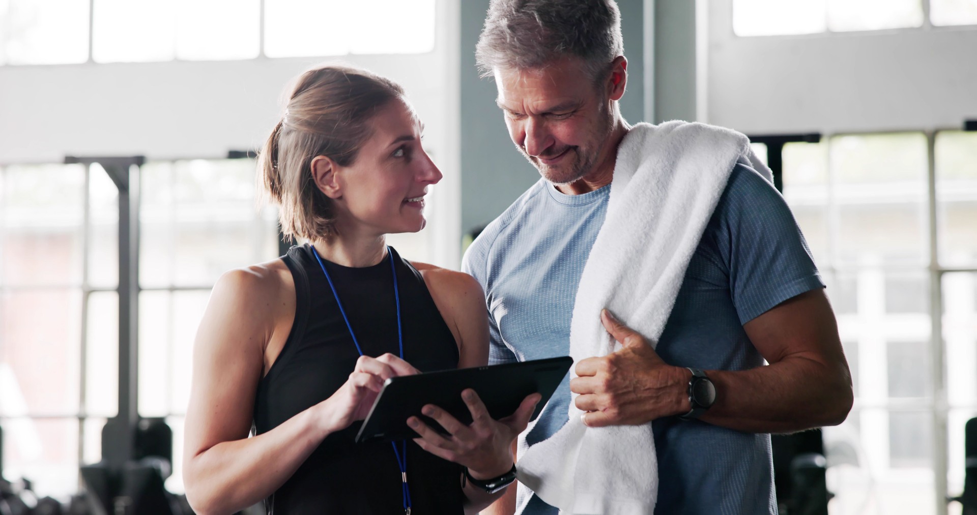 Fitness Trainer Instructor Showing Notes On Clipboard To Woman