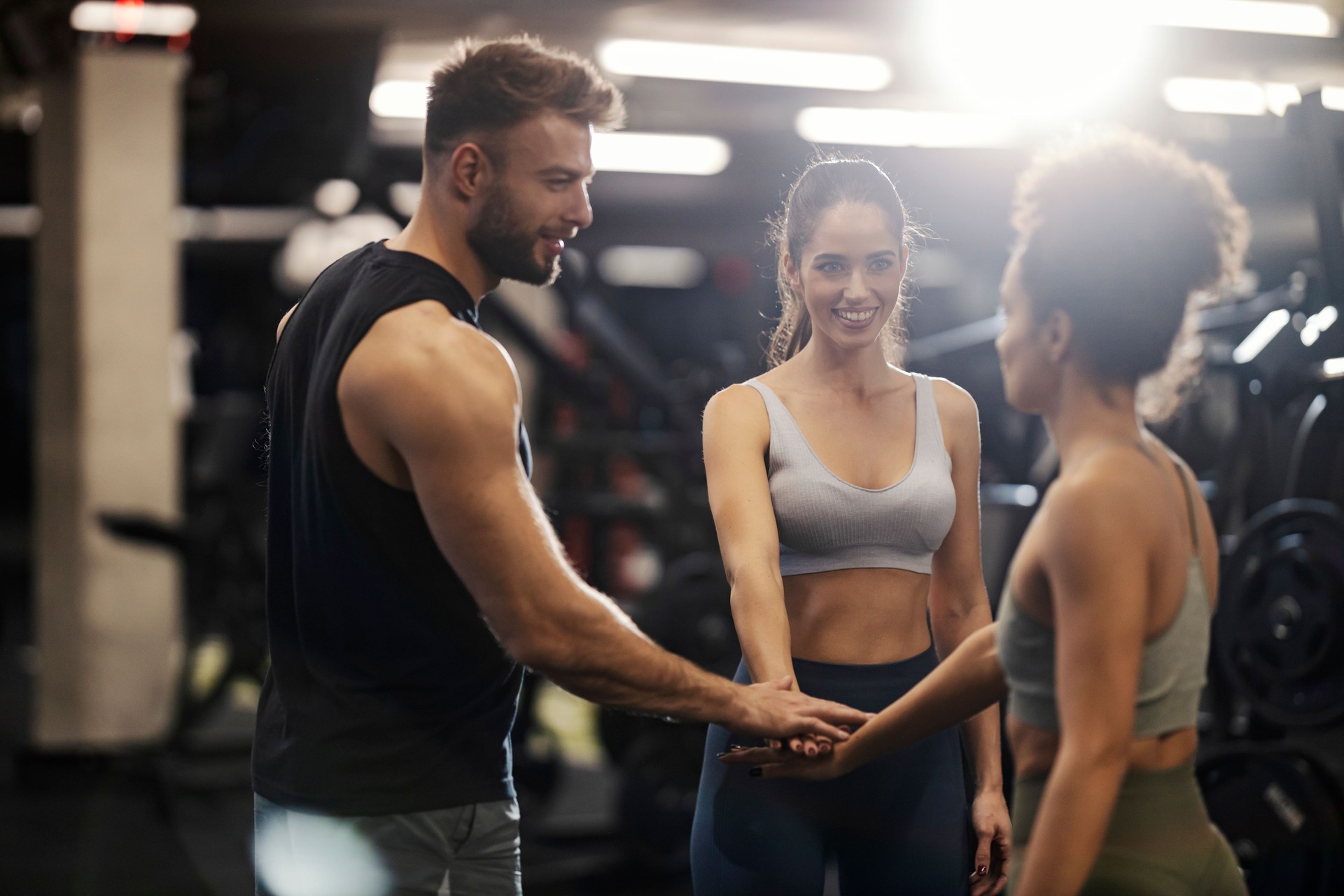 Sportspeople stacking hands in a gym and smiling at each other.